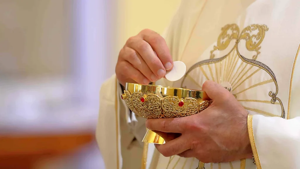 Imagem padre distribuindo a eucaristia do artigo A Igreja vive "da" e "na" Eucaristia