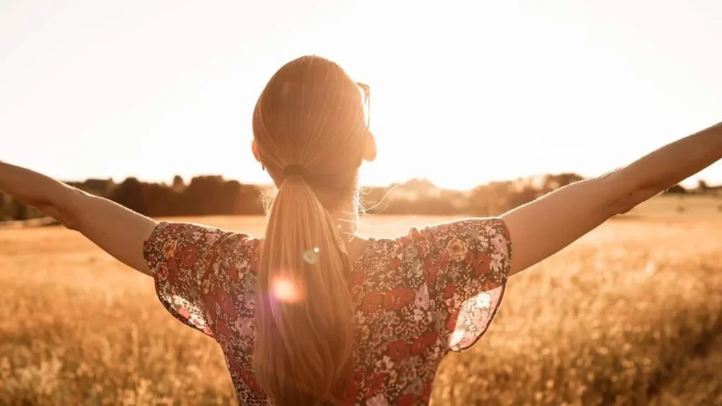 Imagem mulher com os bracos abertos para o sol do artigo Como saber se meus sonhos são vontade de Deus?
