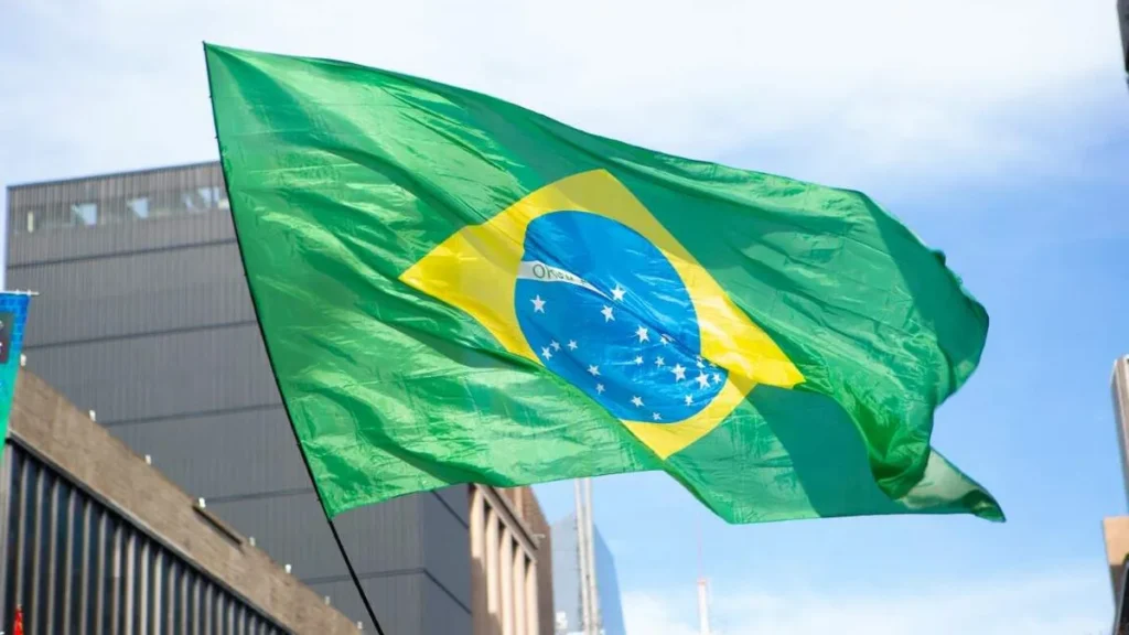 Imagem Bandeira do Brasil balancando em frente a um predio do artigo Brasil e sua história de crises: golpes, prisões e renúncias