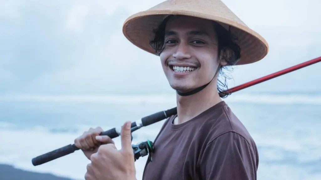 Imagem Jovem pescador sorrindo e com a vara de pescar em maos do artigo Homilia JM - Somos pescadores de Cristo!