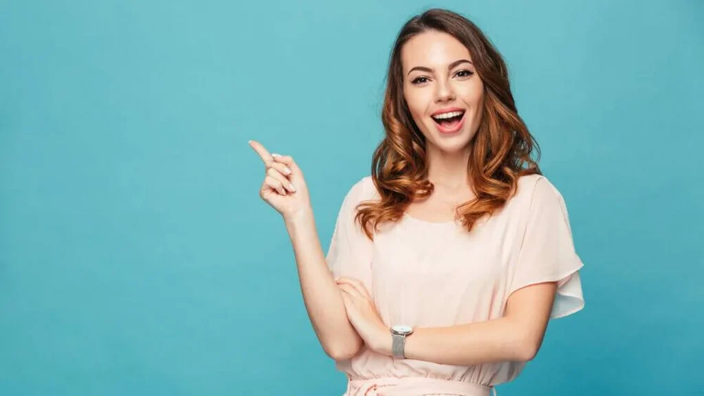 Imagem Jovem feliz empolgada animada aponta para o lado esquerdo do artigo Dia da Mulher: 12 versículos para entender como Deus vê você