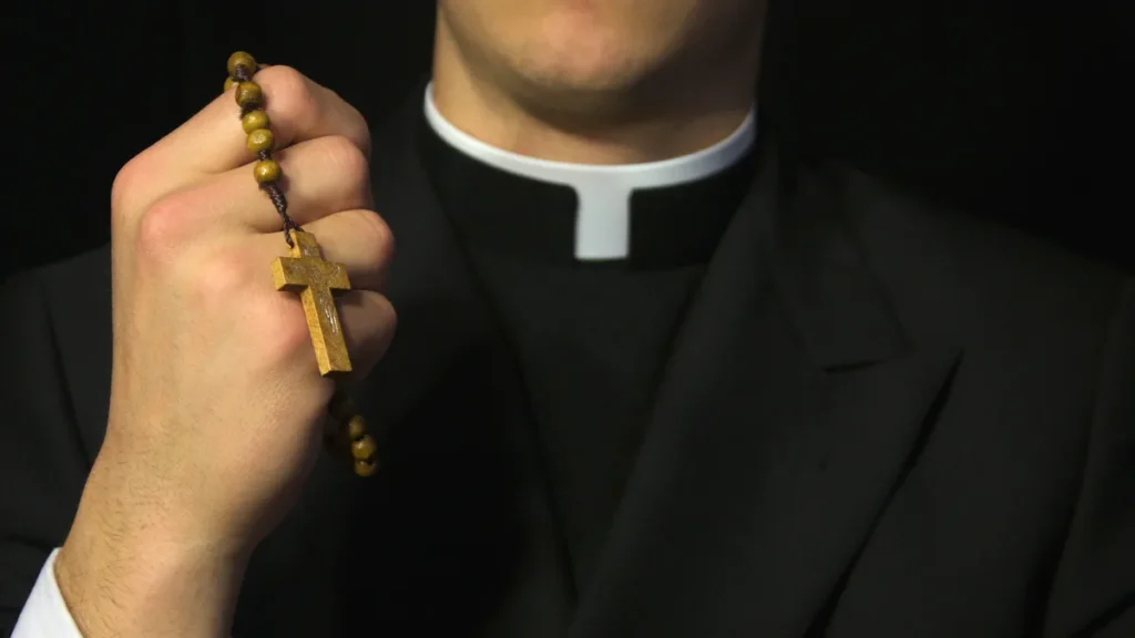 Imagem padre catolico segurando o terco com uma mao do artigo O que significa o celibato na Igreja Católica?