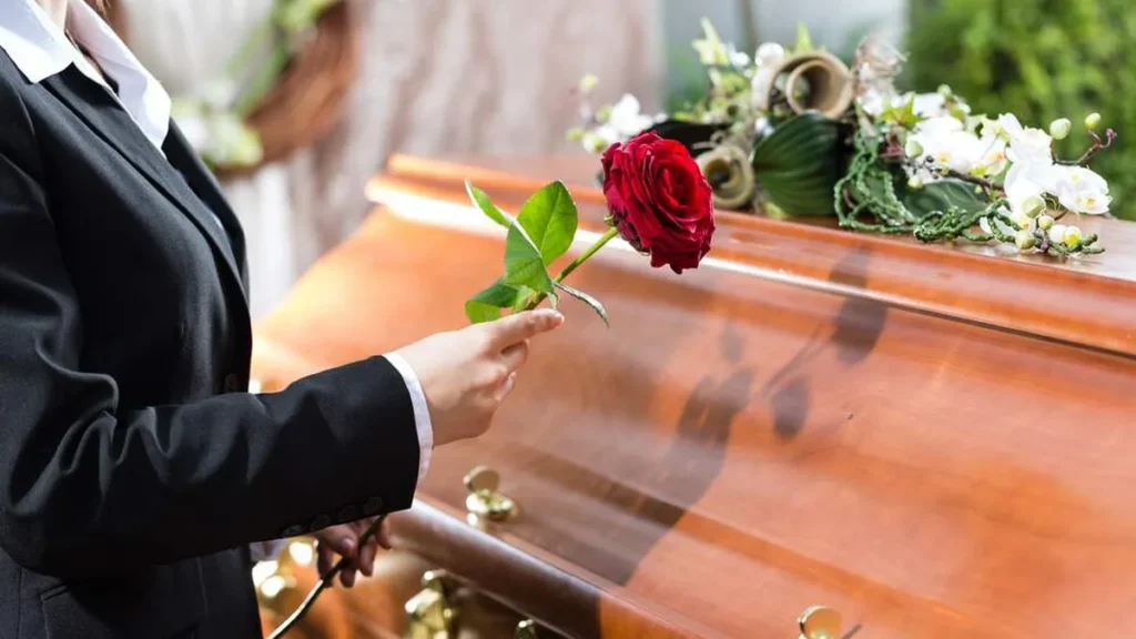Imagem mulher com rosa sobre o caixao do artigo Por que rezar pelos falecidos?