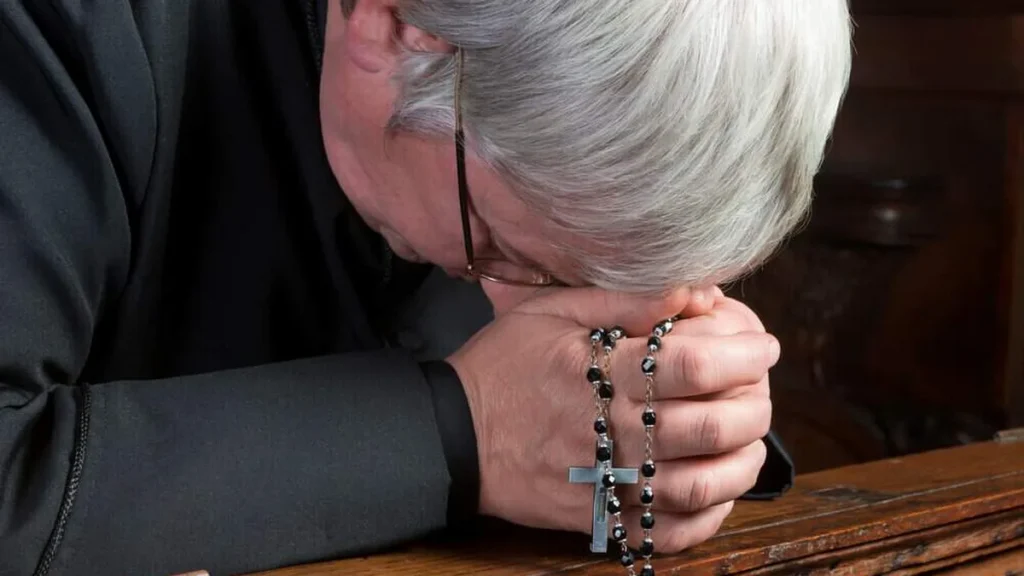 Imagem padre idoso rezando o terco do artigo Por que o Padre não pode se casar?