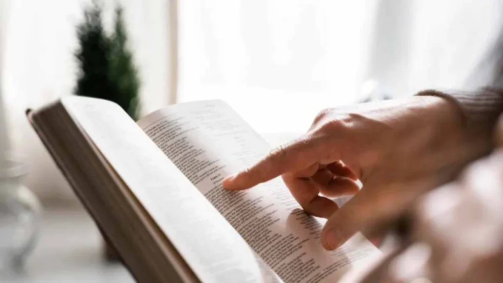 Imagem Vista lateral do homem usando o dedo para ler a Biblia do artigo 4 razões para ler a Bíblia