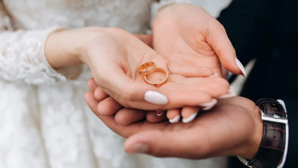 Imagem Noivo segura as maos da noiva onde estao dois aneis de casamento do artigo Matrimônio: casar na igreja é ultrapassado?