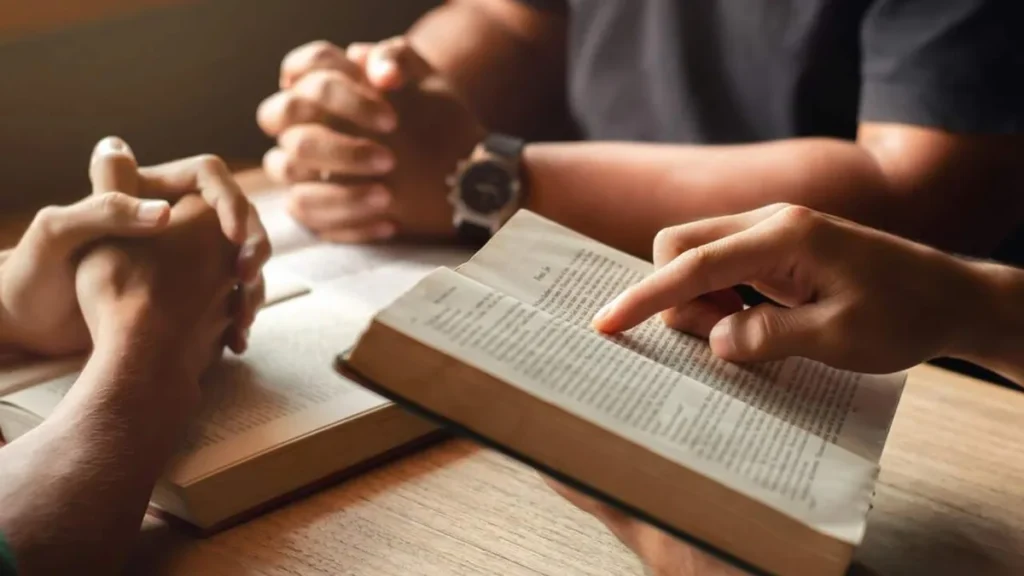 Imagem mao segurando a Biblia com outras maos em volta do artigo A importância da Sinodalidade para a Igreja e seus fiéis