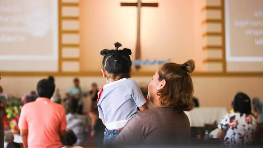 Imagem crianca no colo da mae durante a missa do artigo A plenitude do amor pelo outro