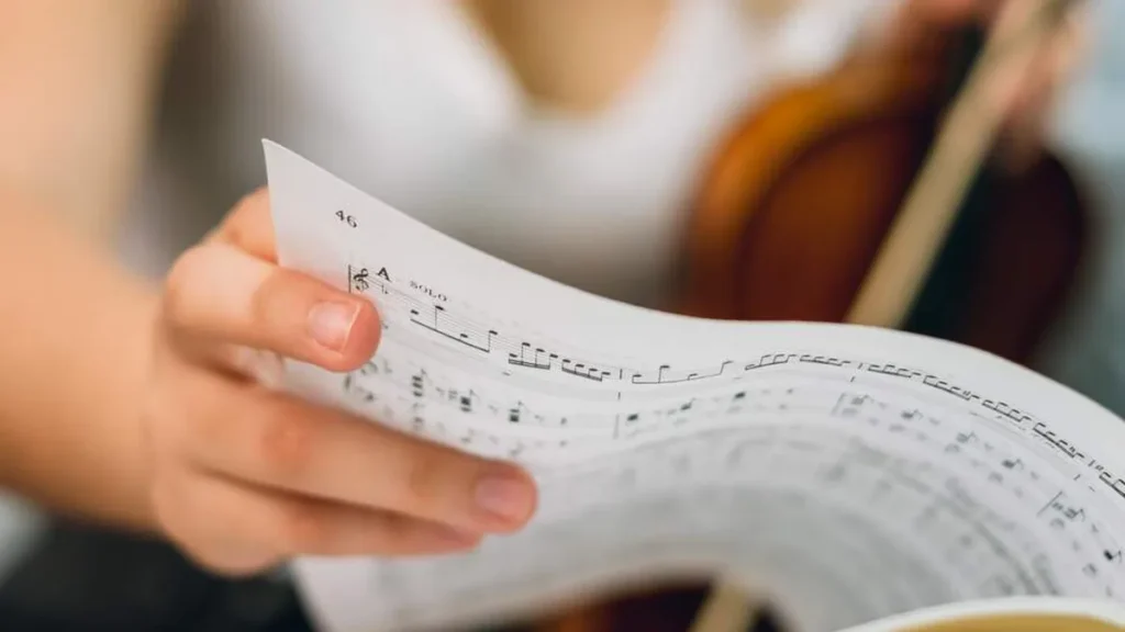Imagem Mao de violinista folhando uma partitura do artigo 4 dicas para você escolher cantos do Advento e Natal