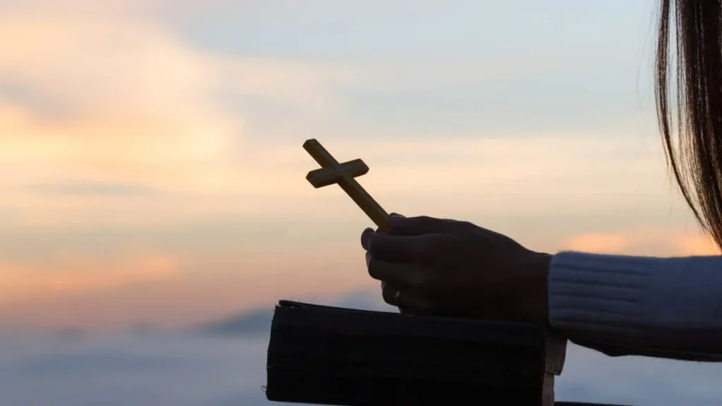 Imagem mulher segurando a biblia e a cruz do artigo Dez versículos para começar bem o ano