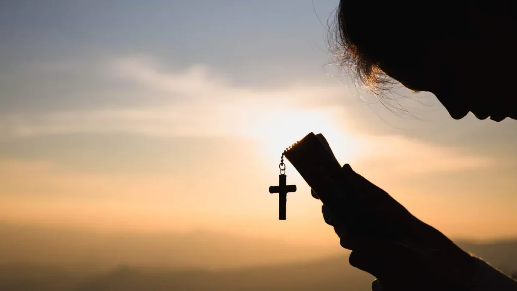 Imagem Silhueta da mulher segurando a Biblia e uma cruz pendurada do artigo Crie metas para sua vida espiritual neste novo ano que inicia
