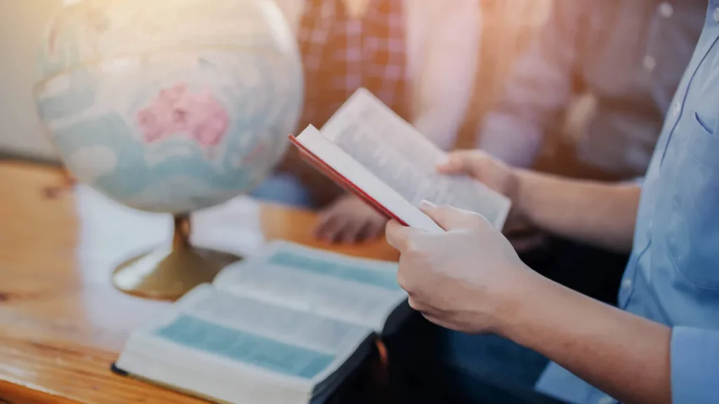 Imagem pessoa segurando biblia e com biblia sobre a mesa do artigo 5 versículos para incentivar você a evangelizar