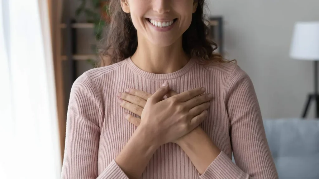 Imagem Mulher sorrindo com as maos sobre o peito em forma de agradecimento do artigo A fé: fonte criadora das belezas da criação