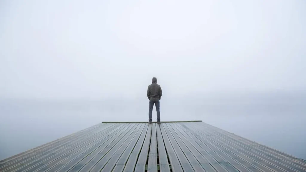 Imagem Pessoa sozinha em cima de desck olhando para o mar do artigo Fazer mais do que falar: o valor do silêncio em nossa vida
