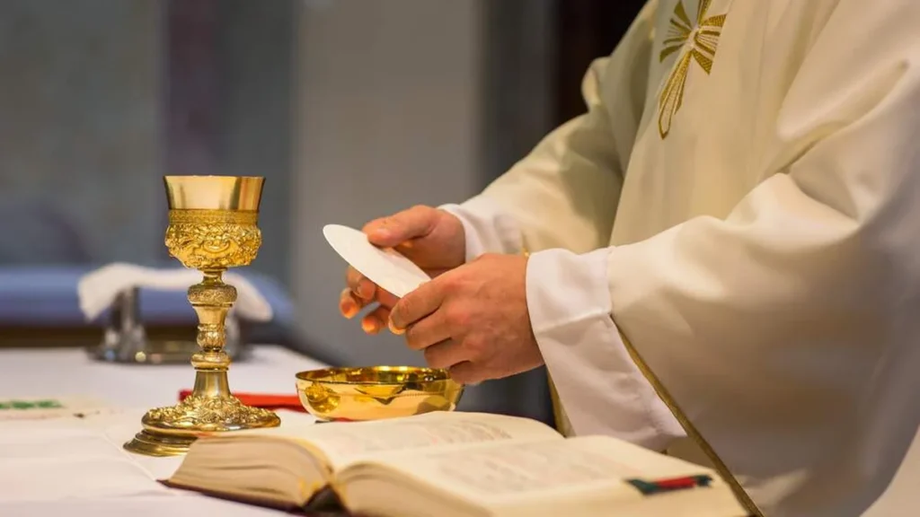 Imagem sacerdote com a hostia grande nas maos durante a santa missa do artigo Por que a hóstia do padre é maior?