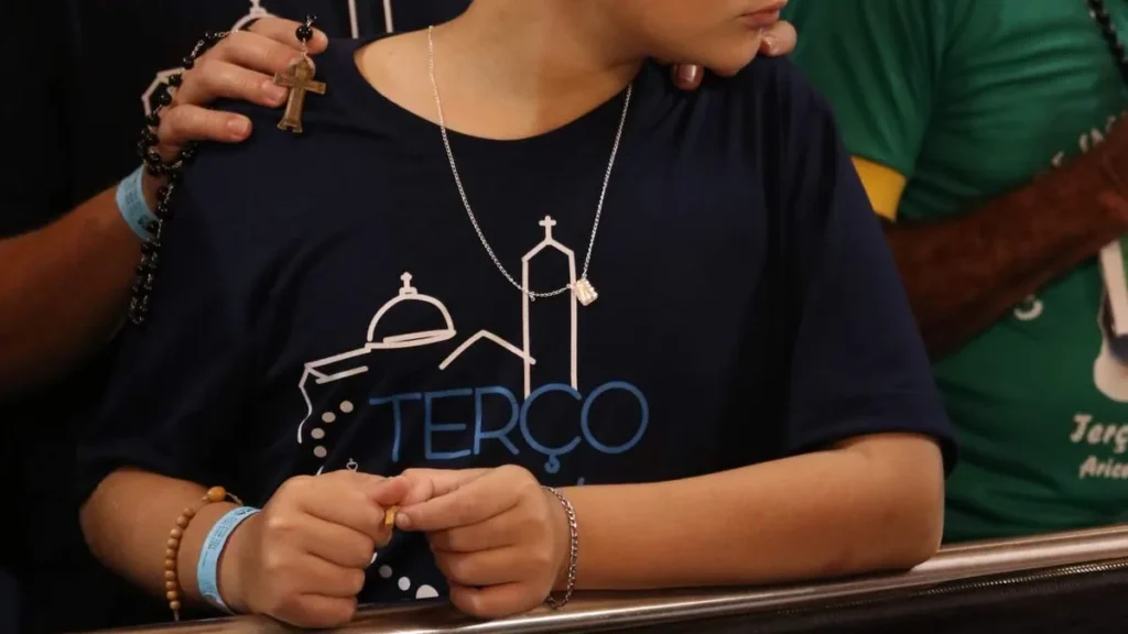 Imagem Missa Abertura Terco dos Homens Mao de pai e filho rezando o terco do artigo Jovens rezam junto de suas famílias o Terço dos Homens