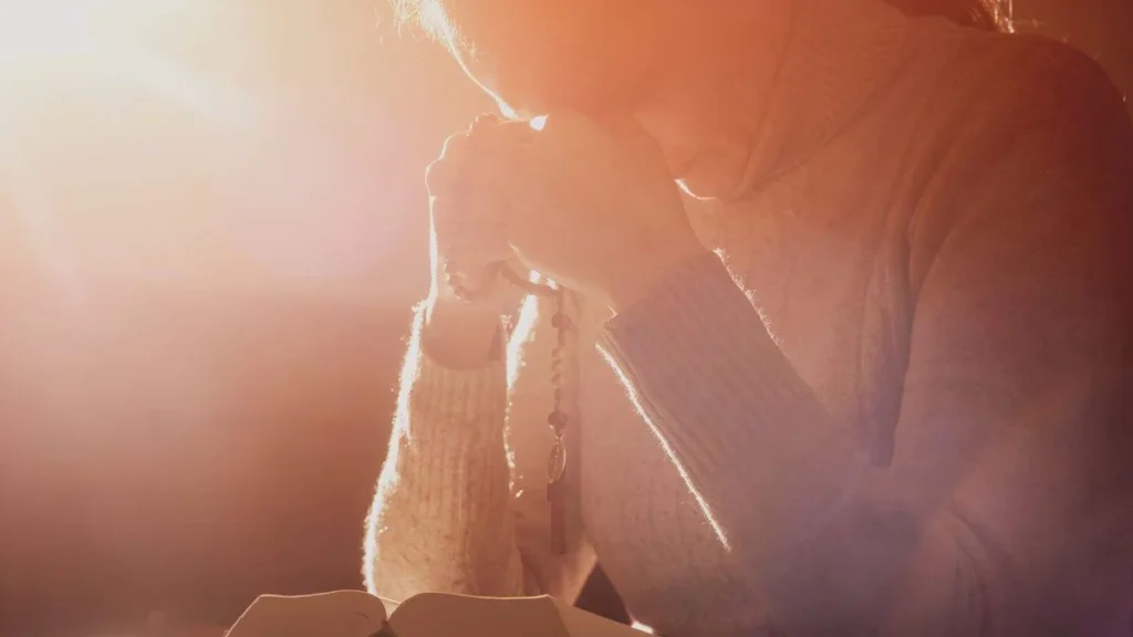 Imagem Mulher em oracao com uma luz ao fundo do artigo Quando rezamos no secreto, abrimos uma porta para o céu