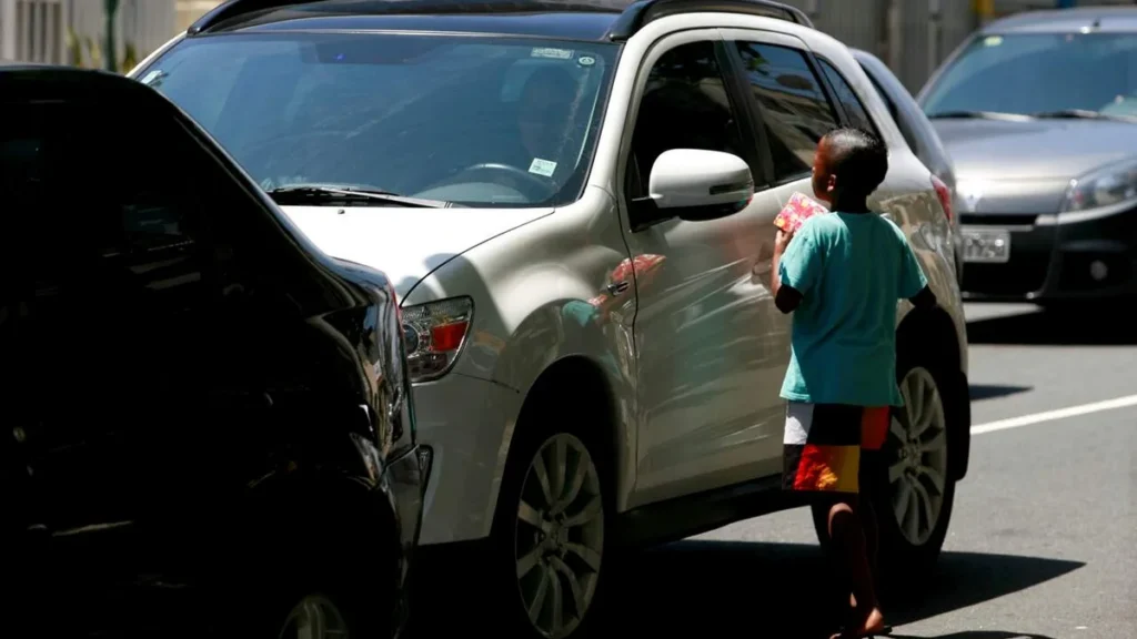 Imagem crianca em semaforo do lado de carro com vidro fechado do artigo Dia Mundial da Infância nos convida a reflexão