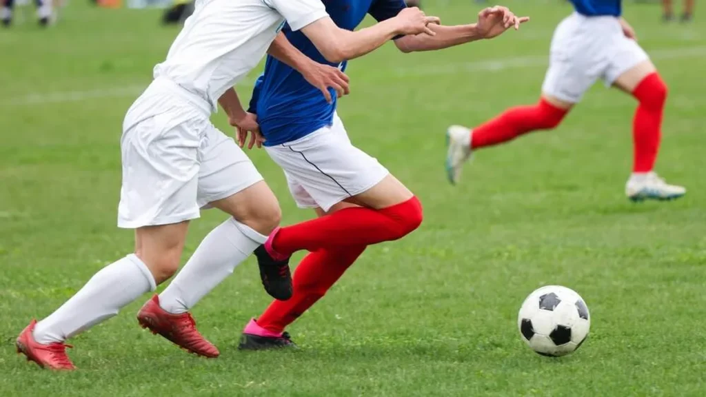Times se enfrentando numa partida de futebol