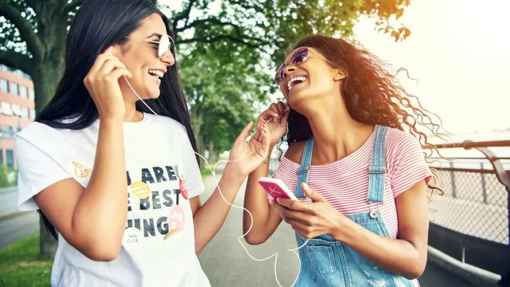 Duas meninas dividindo o mesmo fone para ouvir música