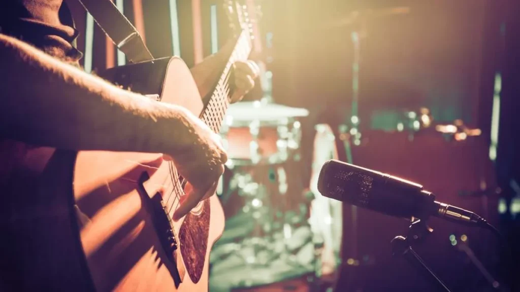 Imagem musico tocando violao para microfone do artigo Esses 4 sucessos sertanejos foram compostos por grandes vozes!