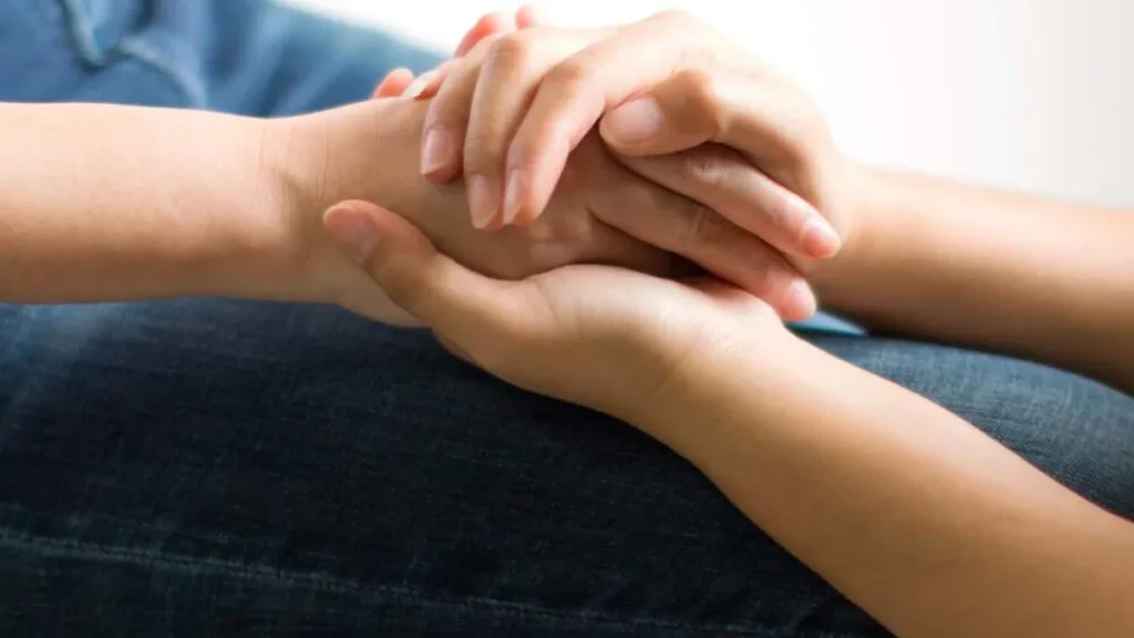 Duas pessoas estão se acolhendo e consolando de mãos dadas