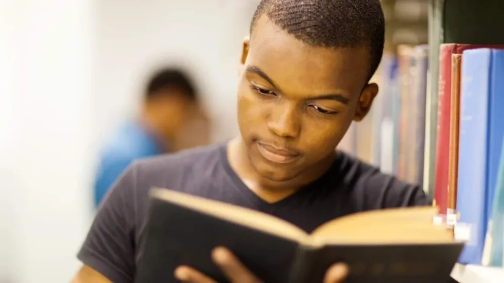 Imagem menino negro lendo livro na biblitoeca do artigo Comece sua jornada missionária inspirando-se nesses 4 livros!