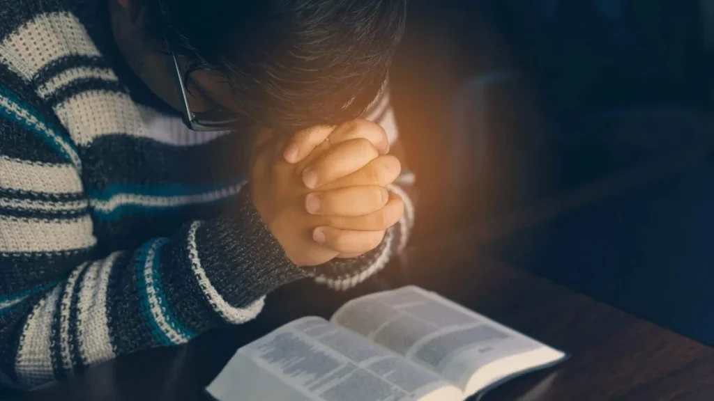 Imagem pessoa rezando sob uma Biblia do artigo Dia de Ação de Graças: Pelo que devo ser grato?