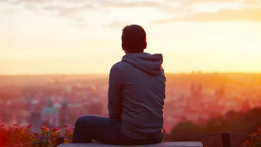 Imagem jovem olhando para o nascer do sol do artigo Virtudes teologais: Esperança