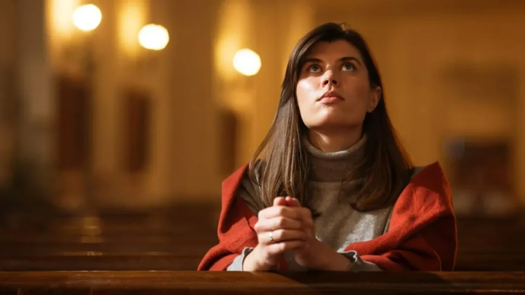 Imagem mulher jovem rezando ajoelhada e olhando para o alto do artigo Se você beber água somente aos domingos, morrerá de sede
