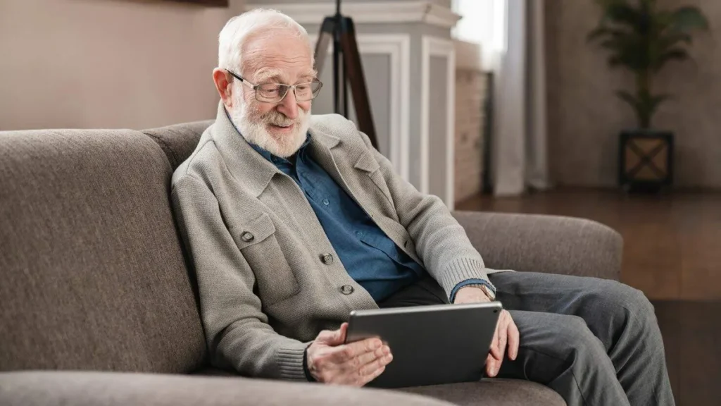 Imagem idoso sentado no sofa assistindo tablet do artigo Padre pode ter um tempo livre para se divertir?