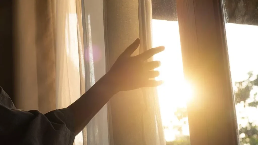 Imagem pessoa com a mao na janela iluminada do artigo A ressurreição de Cristo é a esperança de uma vida eterna para nós