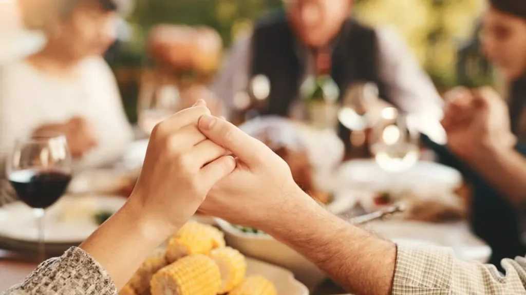 Imagem pessoas rezando antes de fazer a refeicao do artigo Ação de Graças é uma Festa Litúrgica na Igreja?