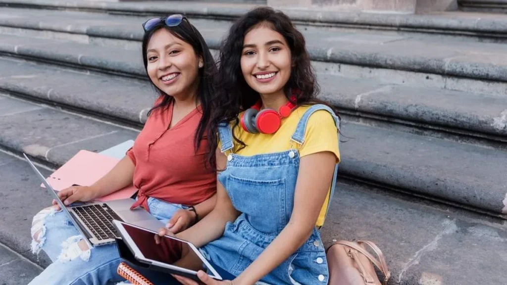Imagem jovens estudando e sorrindo na escada do artigo Jovens solteiras e estudantes: inspirem-se em Santa Catarina de Alexandria!