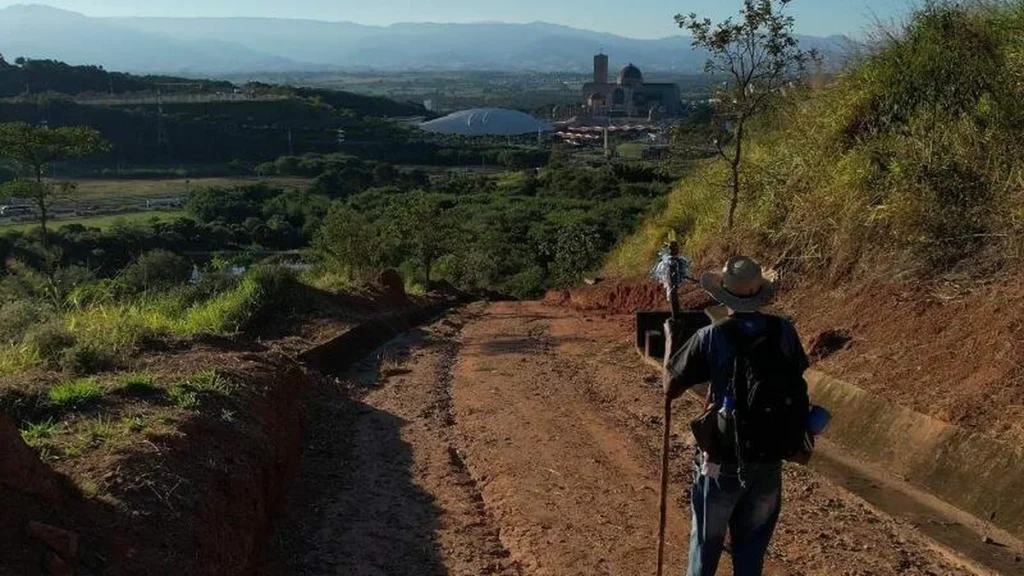 Imagem Romeiro caminhando por estrada de terra com Santuario ao fundo do artigo Somos peregrinos a caminho do Ano Jubilar