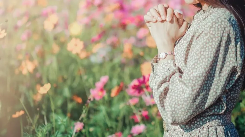 Imagem mulher rezando em meio as flores do artigo Somos “servos inúteis”?