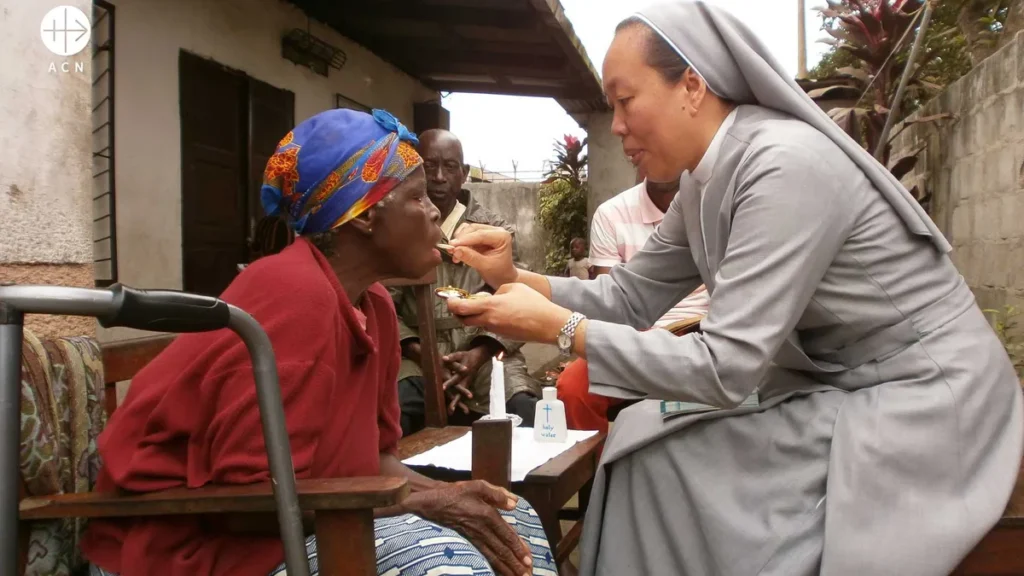 Imagem ACN freira dando hostia a mulher do artigo Trabalho religioso: a profissão mais feliz?