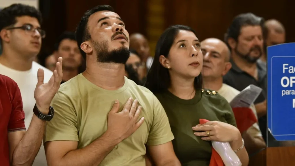 Imagem casal rezando com as maos no coracao olhando a imagem de nossa senhora na missa de natal do artigo Nos últimos dias, reze a oração oficial do Ano Jubilar
