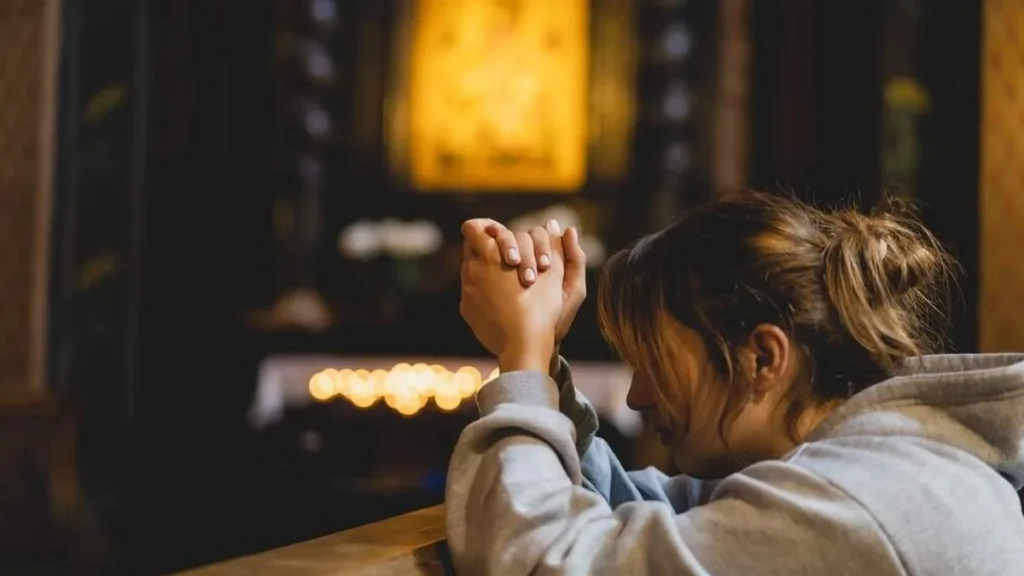 Imagem mulher rezando dentro da igreja do artigo Inicie o ano com fé: reze a Novena de São Sebastião
