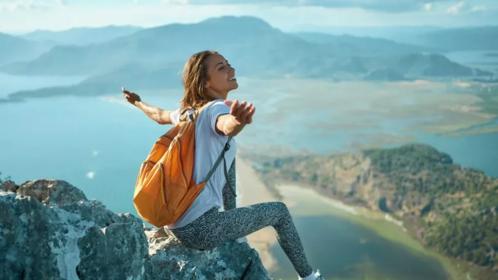 Imagem Mulher em cima de uma montanha contemplando a naturesa do artigo Descubra como se tornar um peregrino de si mesmo
