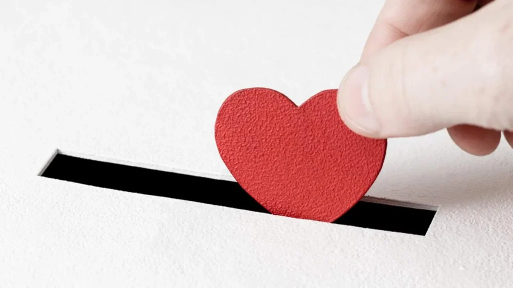 Imagem Homem depositando um coracao o amor em uma urna do artigo Como exercer a caridade no tempo da Quaresma?