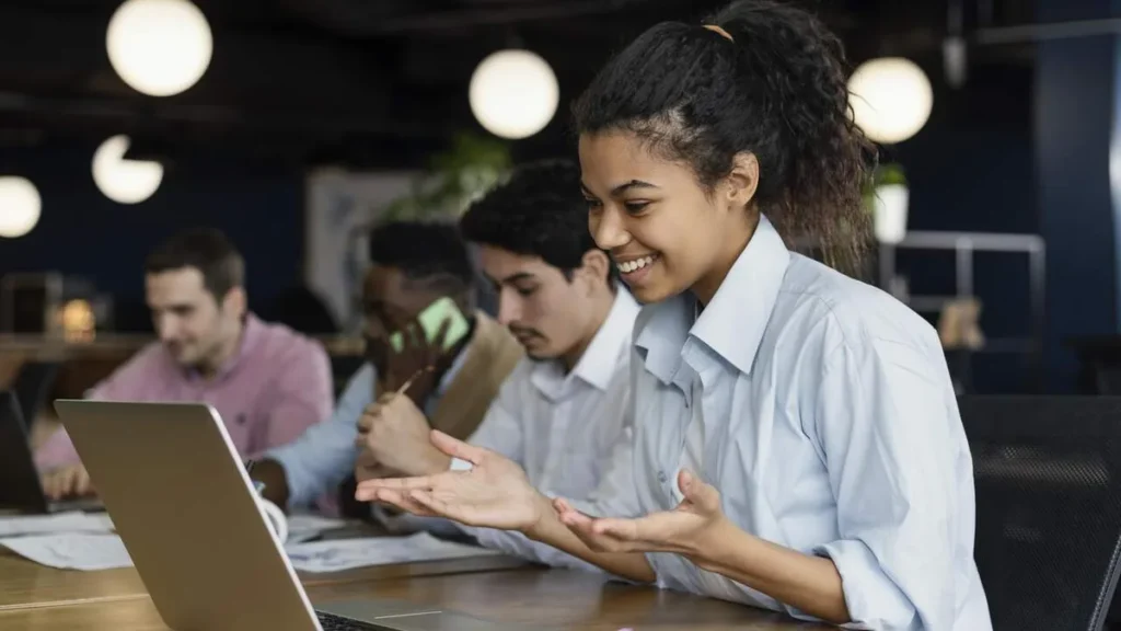 Imagem Mulher sorridente na frente do computador do artigo A importância da Comunicação clara e eficaz no ambiente de trabalho