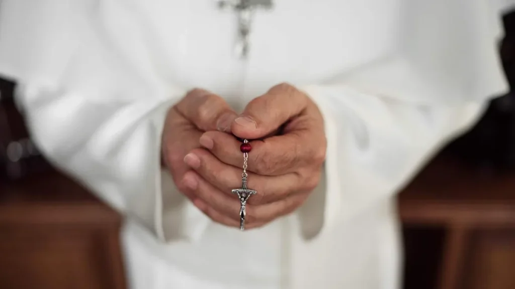 Imagem mao de um papa segura o rosario mostrando o crucifixo a frente do artigo O que os Papas dizem sobre rezar o terço?