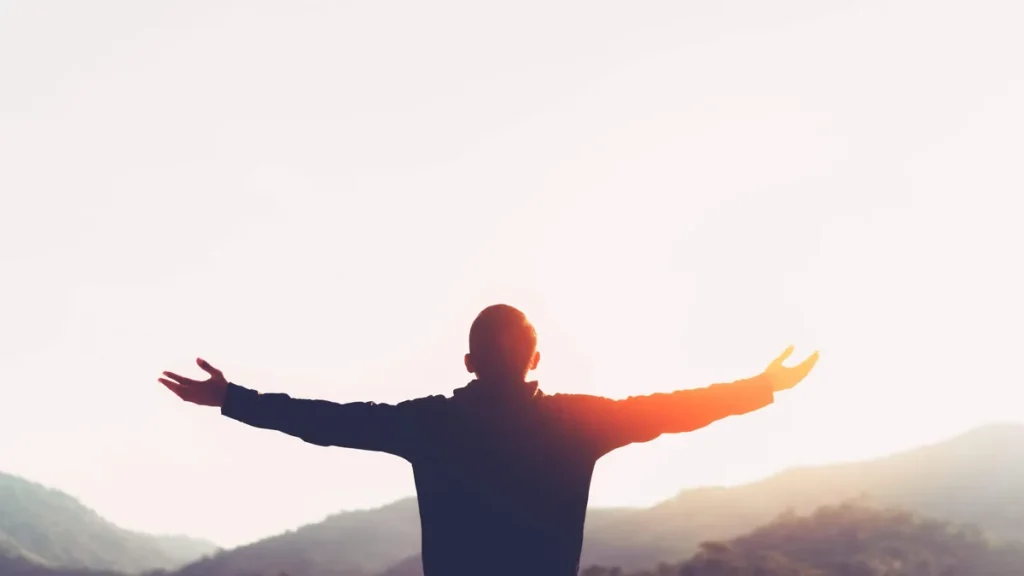 Imagem homem com os bracos abertos para o sol do artigo Por que viver com sentido é mais urgente do que nunca?