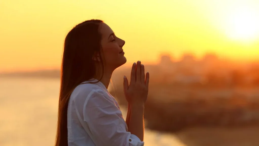 Imagem Mulher rezando por do sol do artigo Aprenda a rezar com os Salmos de forma simples