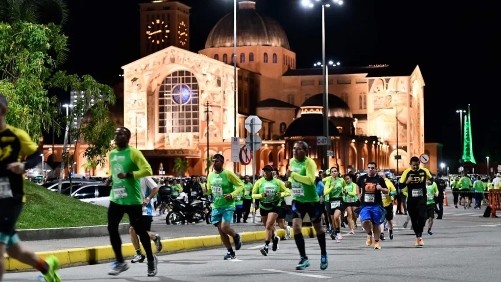 Imagem Pessoas correndo a noite em frente a Fachada Sul do Santuario Nacional toda iluminada do artigo Veja as novidades da Corrida Mãe Aparecida 2026