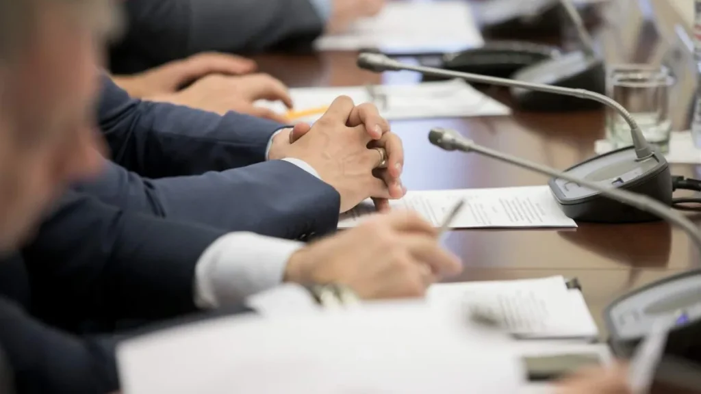 Imagem politicos em mesa conversando com foco nas maos do artigo O que está por trás da Teologia do Domínio?