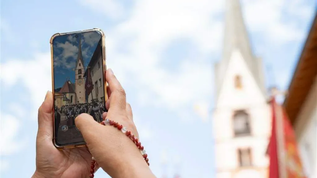 Mão segurando celular fotografando igreja