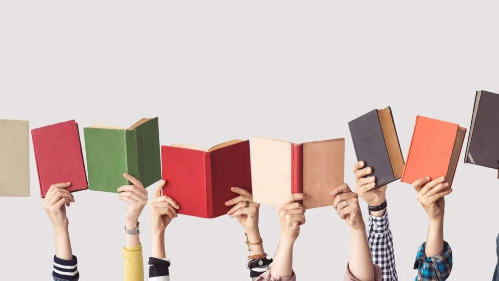 Imagem varias pessoas segurando livros com as maos e erguendo para o alto do artigo Semana do Livro: 7 leituras para repensar o presente