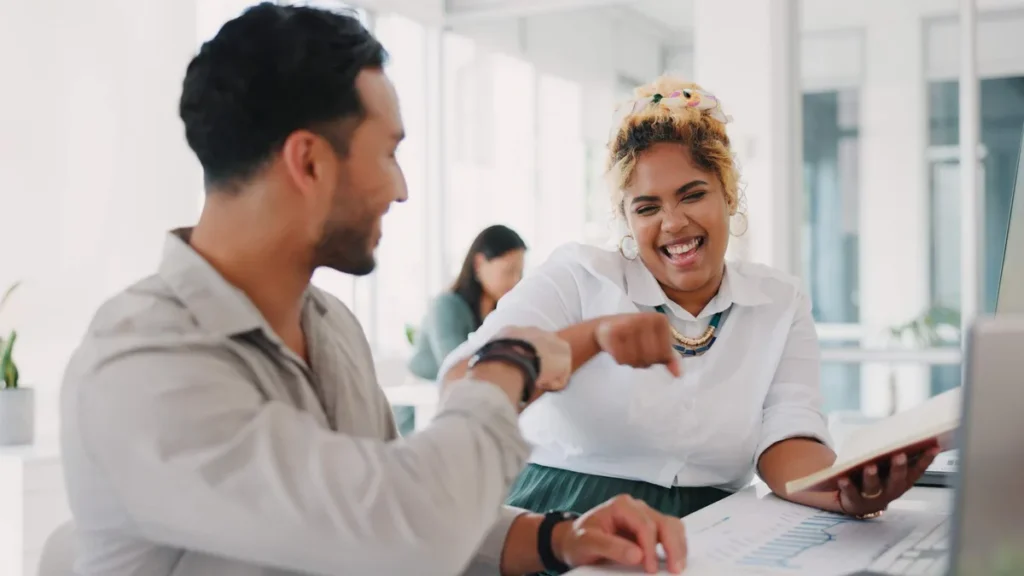 Imagem colegas de trabalham se cumprimentam felizes em ambiente de trabalho do artigo Gentileza: o segredo para transformar o ambiente no trabalho